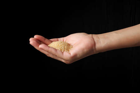 Hand holding brown sugar isolated on black backgroundの写真素材