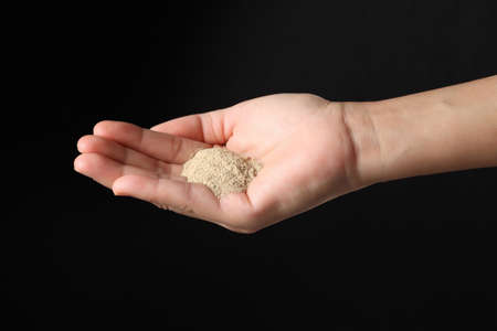 Hand holding ground pepper isolated on black background