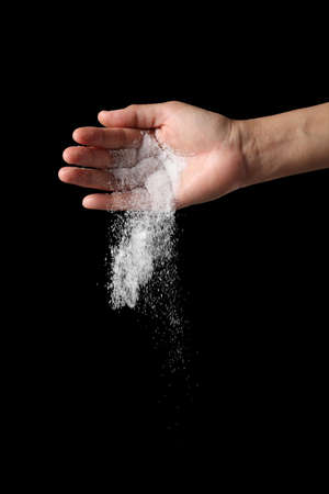 Hand holding salt isolated on black backgroundの写真素材