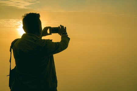 Traveler standing at Viewpoint on top of a mountain take a picture and enjoying sunrise.の写真素材