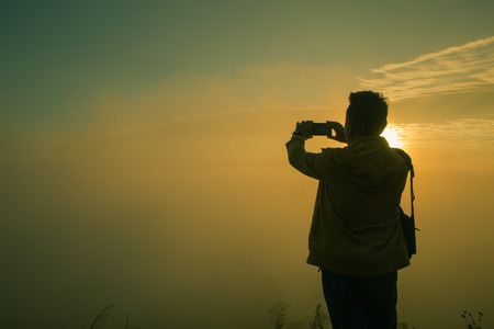 Traveler standing at Viewpoint on top of a mountain take a picture and enjoying sunrise.の写真素材