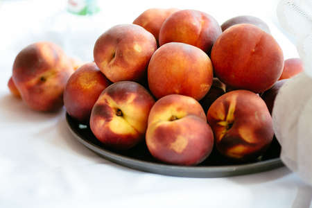 Summer tasty peaches on a plate with white backgroundの写真素材