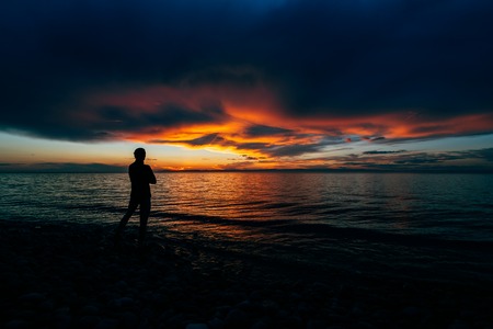 Silhouette of man on the shore of a lake sunset background, baikal, Russiaの写真素材