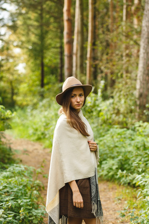 A girl in an ethnic poncho and a hat in a pine forestの写真素材
