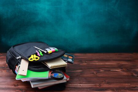 Back to school concept. School bag, pencils, crayons, scissor, notebooks, alarm clock, eraser, markers, watermark ruler, pencil sharpener, magnifying glass in a combine with a cyan backgroundの写真素材