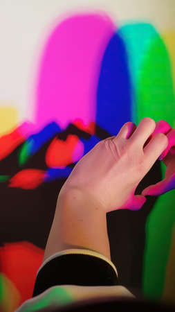 A closeup shot of a person's hand touching a colorful backgroundの写真素材