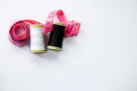 Spools of black and white thread and a measuring tape on a white background.の写真素材