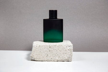 Cosmetic bottle with green liquid on concrete podium on gray background. Beauty product presentation.の写真素材
