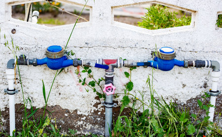 Water pipes and valves on the wall of a building in the gardenの写真素材