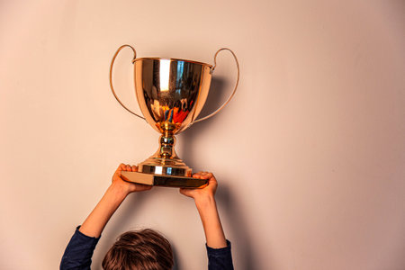 A boy holding a trophy on a white background. The concept of success and victory.の写真素材