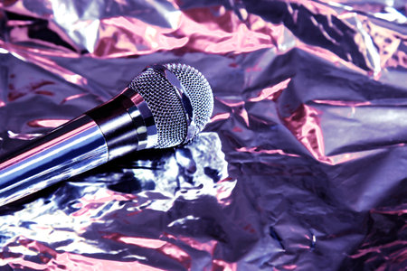 silver microphone on foil blurred neon purple and pink background, music voice sound concert conceptの写真素材