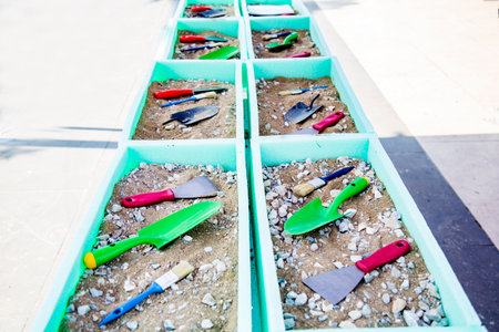 Trowel, brush and shovel on the sand, close-up, archeology educations concept