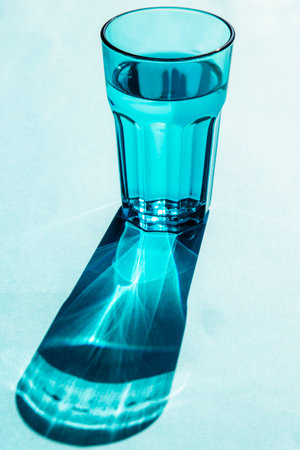 blue glass with water and shadow, isoladet on a blue background verticalの写真素材