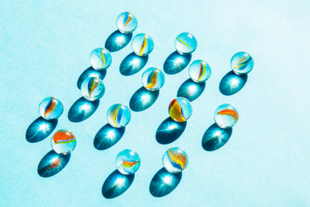 blue glass spheres with shadows on blue background, abstract pattern top view