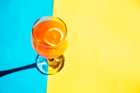 orange color cocktail with lemon on blue and yellow background with copy spaceの写真素材