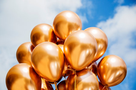 golden balloons on blue sky background. holiday and celebration concept.の写真素材