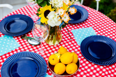Table set for dinner in the garden with flowers and lemons on tablecloth
