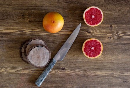 Grapefruit and a knife on a wooden table. Top view