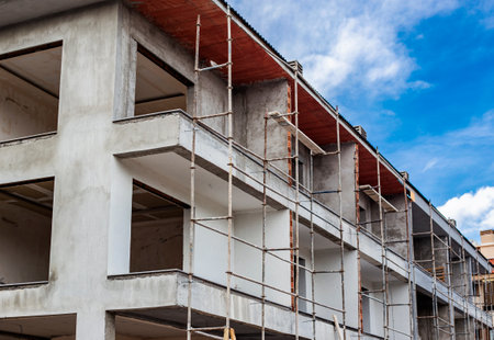 Multi-storey building under construction with scaffolding against blue sky