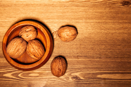 Walnuts in a wooden bowl on a wooden background. Toned.