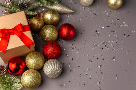 gift box with red ribbon and colorful Christmas decorations on gray background invitation card with copy spaceの写真素材