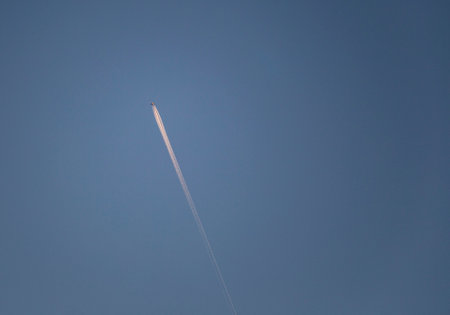 Airplane in the blue sky with white trace of the plane.