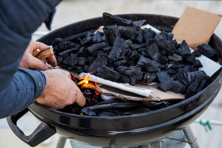 A man burns a piece of coal in a barbecue. Close-up.
