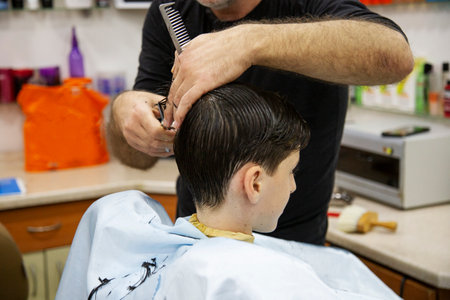 Hairdresser cutting boy's hair in a barber shopの写真素材