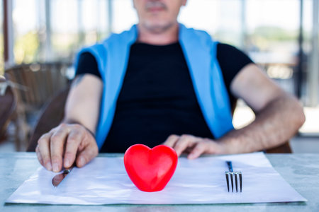 Man's hands and heart on the plate, emotional diet physical health through what we eatの写真素材