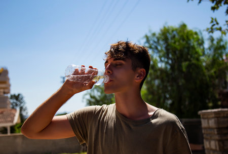 Portrait of a young man drinking water from a plastic bottle outdoorsの写真素材
