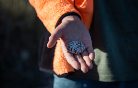 Little boy holding a stone in his hand. Selective focus.の写真素材