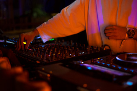 DJ playing music at the nightclub. Close-up of male hands mixing music on midi controller.