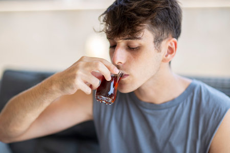 Young handsome man drinking tea in a cafe. Close-up portrait of an attractive man enjoying teaの写真素材