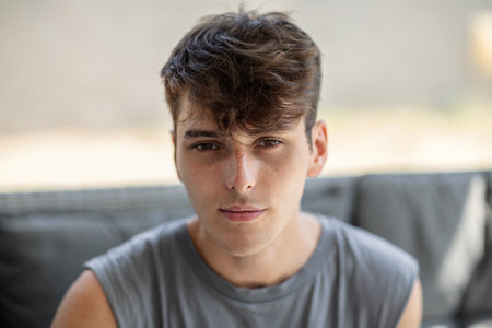 Portrait of handsome young man sitting on sofa and looking at camera and smiling