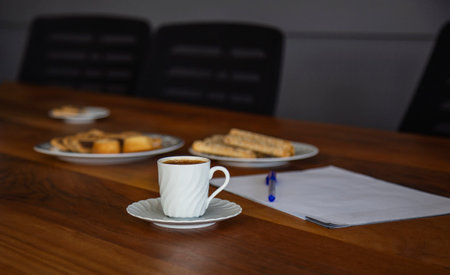 Coffee cup cookies and cardboard on wooden table in office
