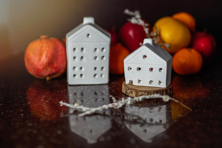 Miniature ceramic houses with pomegranate and fruits on a black background, abstract still lifeの写真素材