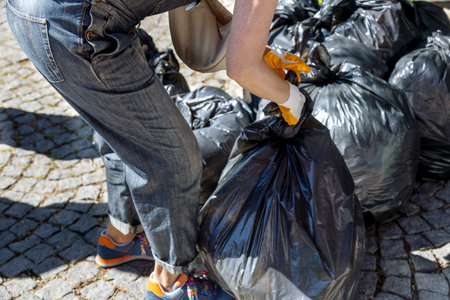 Volunteer collecting garbage in the street. Selective focus.