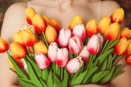 Young woman embraces a bouquet of tulips close-up without face selective focusの写真素材