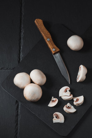 Sliced champignons on a board next to a knifeの写真素材