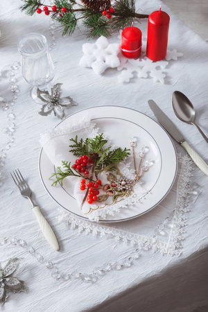 Festive table setting with a white tablecloth and plates. Decoration for the New Year and Christmasの写真素材