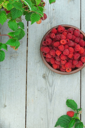 Raspberry berry fresh in a clay plate on a wooden background, top viewの写真素材