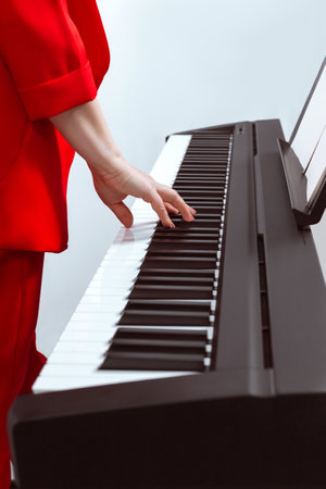 The girl plays the piano with one hand. Pianist's hand on the keys close-up. Partial focusの写真素材