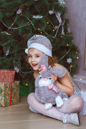 A cute girl with a stuffed rabbit looks at the camera with mischiefの写真素材