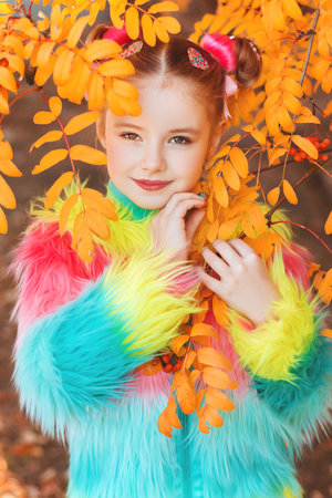 A girl in colored clothes among autumn yellow leaves of rowanの写真素材