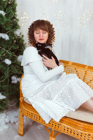 A woman in a white dress hugs a black rabbit. The relationship of a person with a petの写真素材