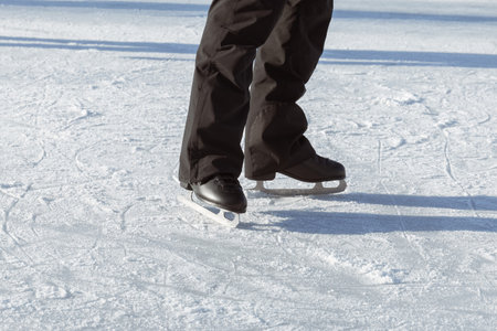 Men's legs in black skates close-up on the rink. Going for a ride. Active winter holidaysの写真素材