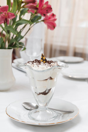 Dessert of sponge cake and whipped cream in a transparent cream bowl on the tableの写真素材