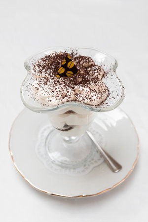 Dessert of sponge cake and whipped cream in a transparent cream bowl on the tableの写真素材