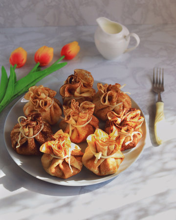 Serving the table for Maslenitsa with pancakes in the form of bags, milk and tulipsの写真素材