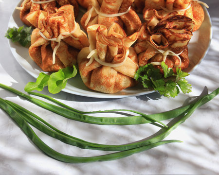 Pancakes with filling in the form of bags tied with cheese, close-up. A traditional dish for the Maslenitsaの写真素材